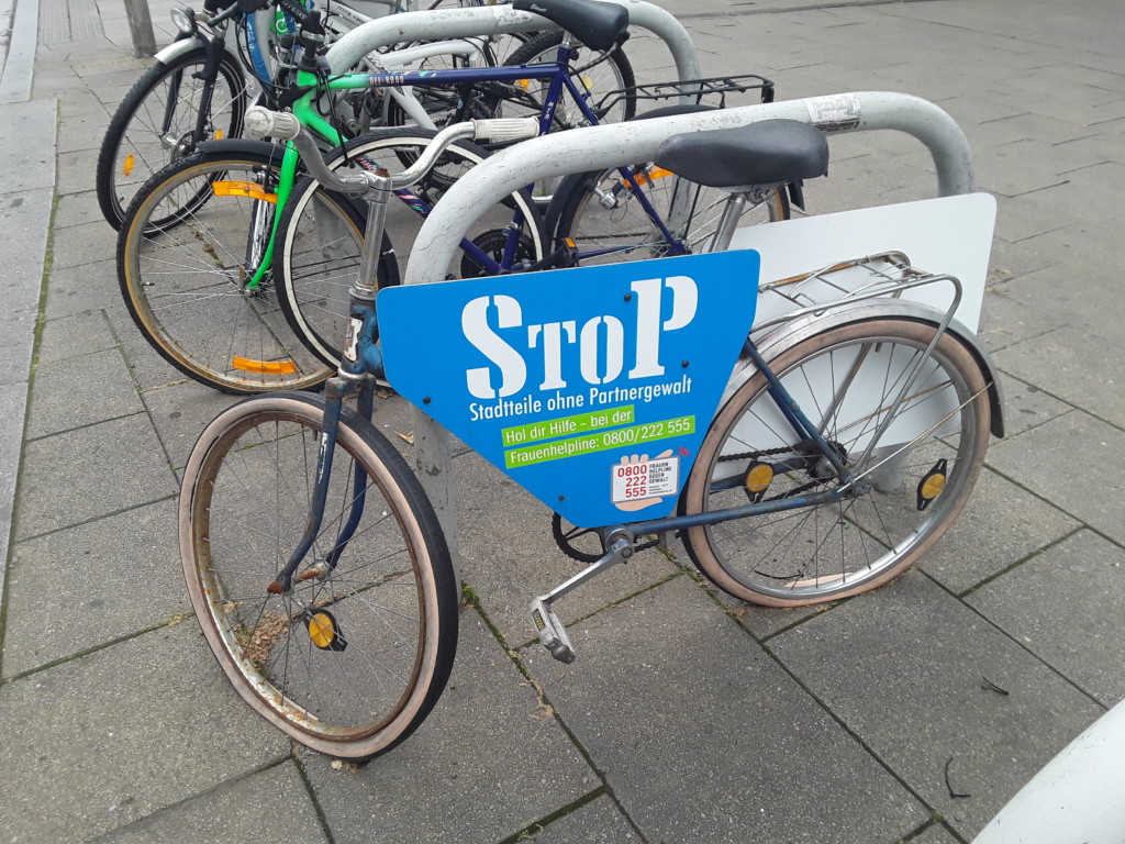 Fahrrad mit Werbetafel "Stop -Stadtteile ohne Partnergewalt" am Radständer