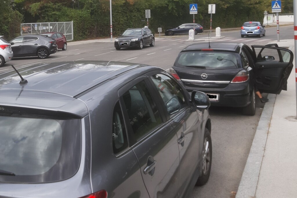 Autos am Straßenrand, eine geöffnete Autotüre, wo jemand aussteigt