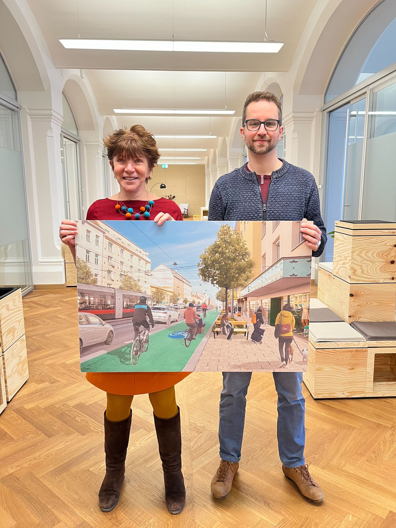 Eine Frau und ein Mann halten eine großes Bild, das eine Vision von der Brünner Straße mit Radweg darstellt.