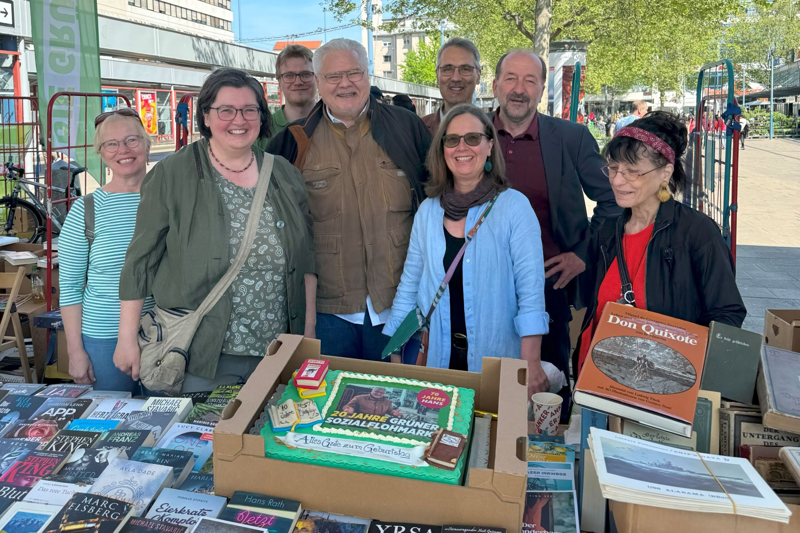 Mehrerer Personen stehen hinter einem Tisch mit Bücher, auf dem Tisch steht auch eine große Torte