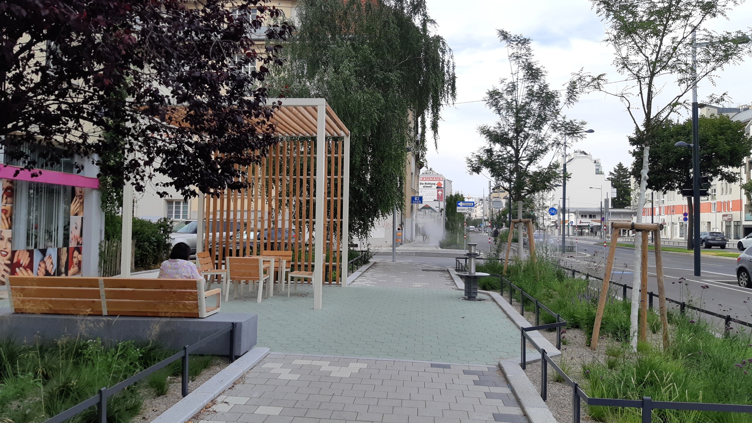 Breiter Radweg mit beidseiitigen Pflanzenbeeten sowie Sitzmobiliar.