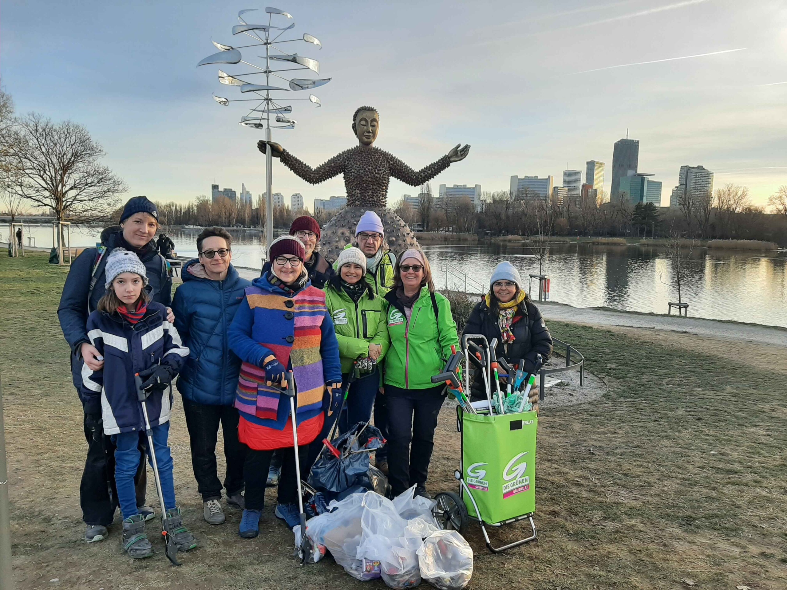 Gruppe von Menschen bei der Alten Donau mit Greifzangen und gefüllten Mistsäcken