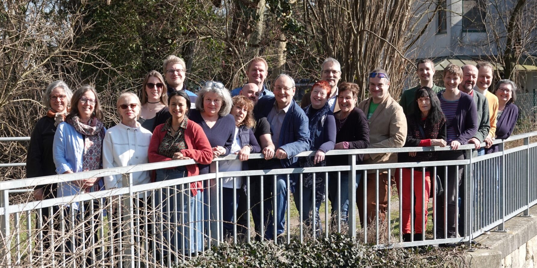 Gruppenbild in der Natur mit 21 Personen an einem Brückemgitter