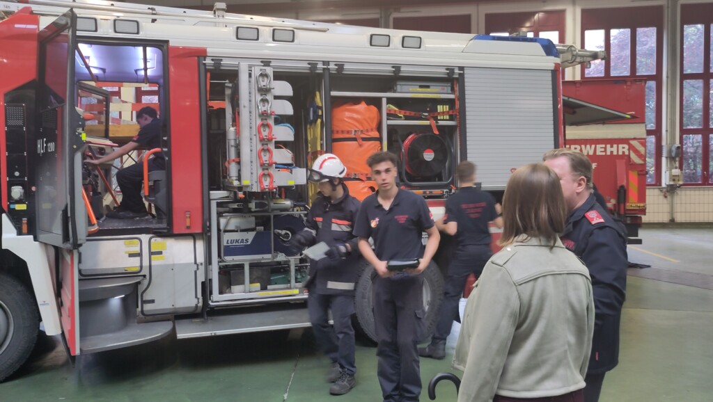 Ein Feuerwehraufo, vor dem einige Menschen stehen