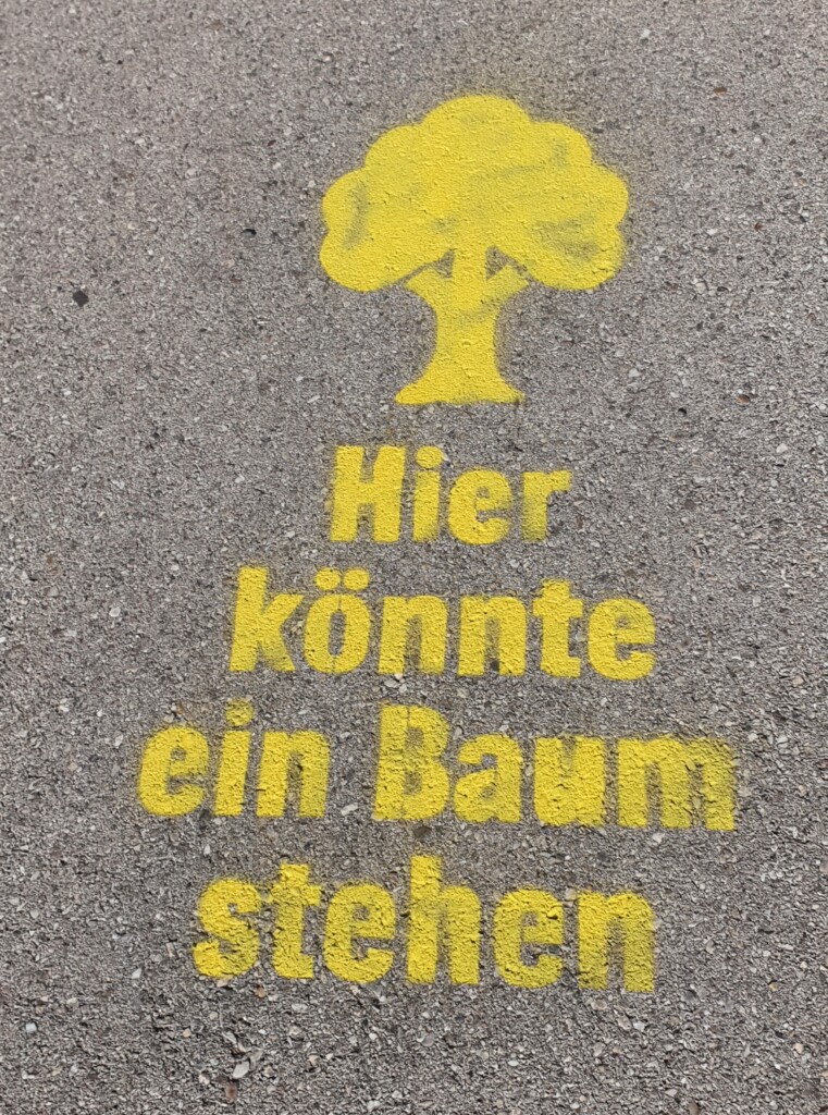 Aufgemalter Baum auf Asphalt mit dem Text "Hier könnte ein Baum stehen"